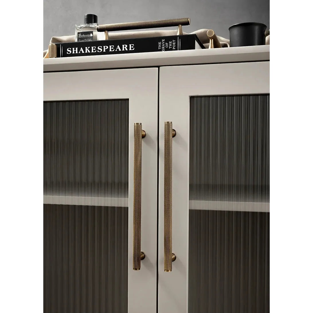 Moderne kast met lange goudkleurige deurgrepen van Aurel luxury hardware op glasdeuren.