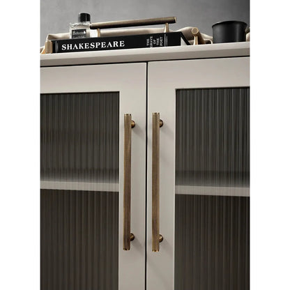 Moderne kast met lange goudkleurige deurgrepen van Aurel luxury hardware op glasdeuren.