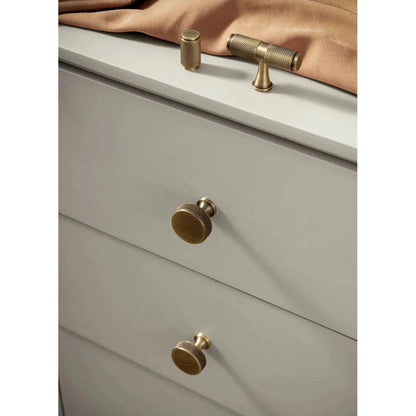Gouden knoppen en grepen op een beige ladekast, luxe meubelbeslag van Aurel voor interieur.